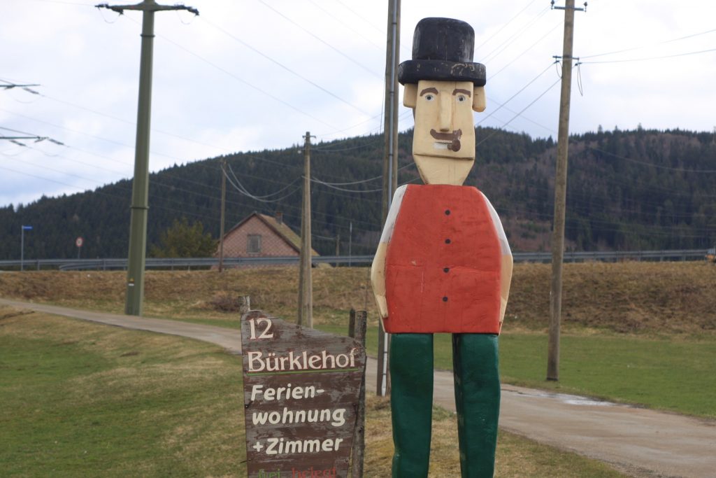 Holzfigur im Schwarzwald weist auf Ferienhof