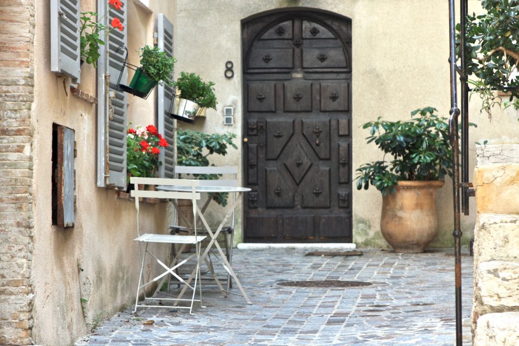 Tisch und zwei Stühle vor einem Eingang und Blumenfenster in Antibes