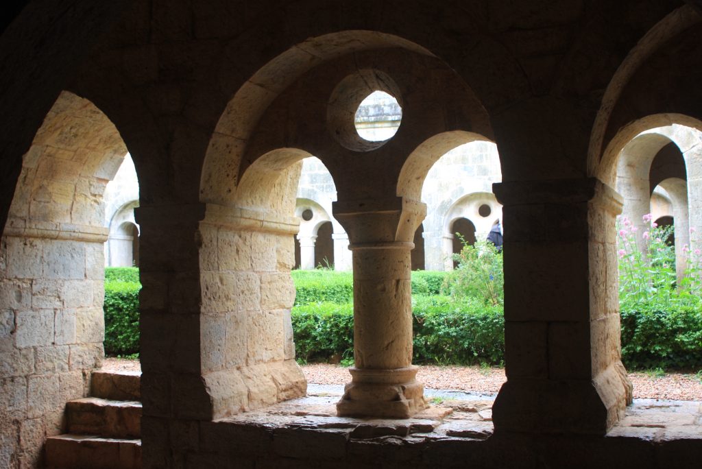 Blick durch die Bögen des Kreuzgangs in den grünen Innenhof