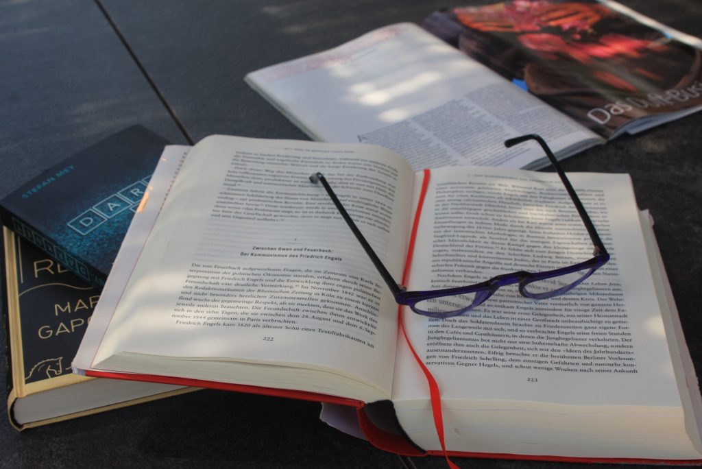 Stapel Bücher, aufgeklappt und eine Lesebrille