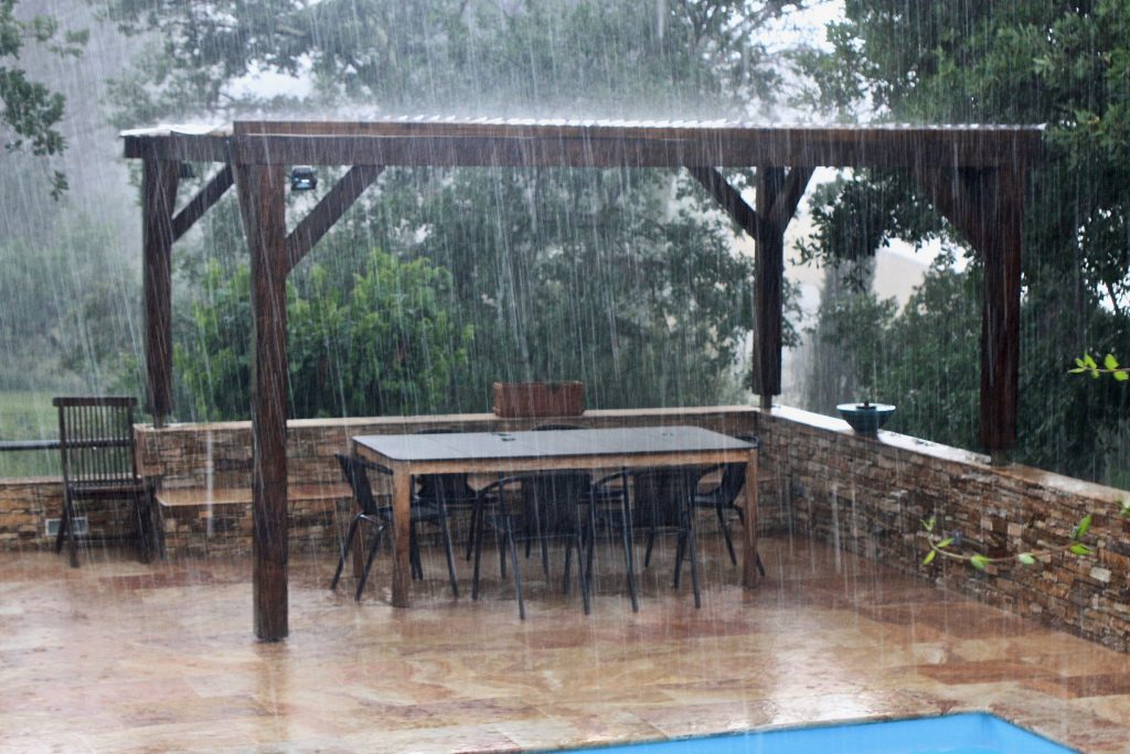 Pergola mit Tisch und Stühlen bei strömendem Regen