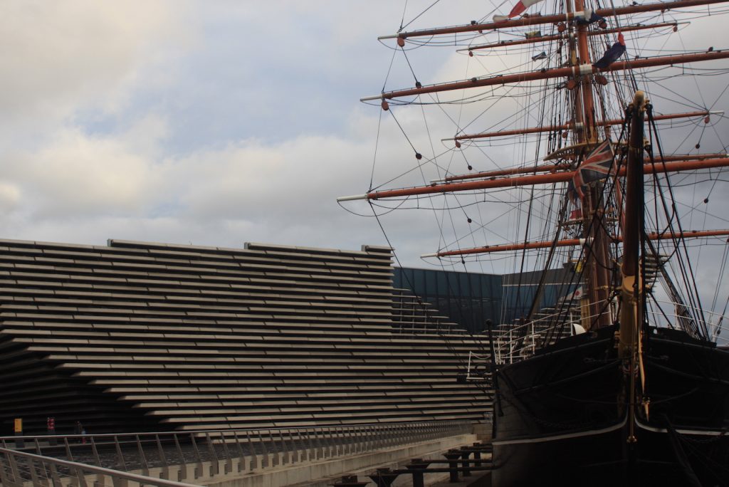 Moderne Fassade neben altem dreimastigen Segelschiff