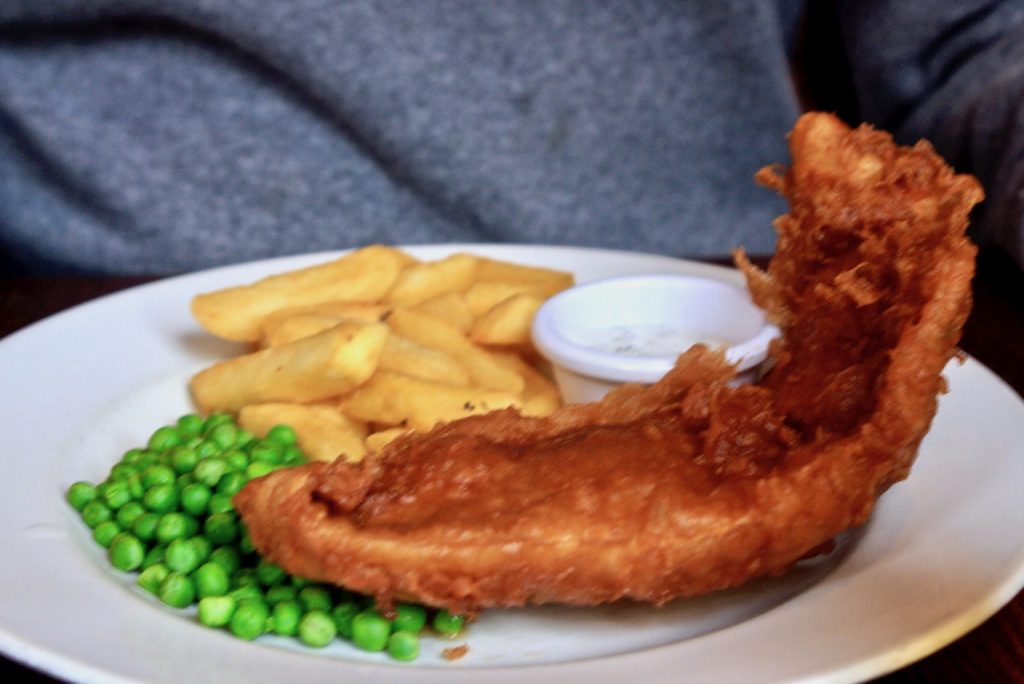 Pommes und parnierter Fisch mit Erbsen